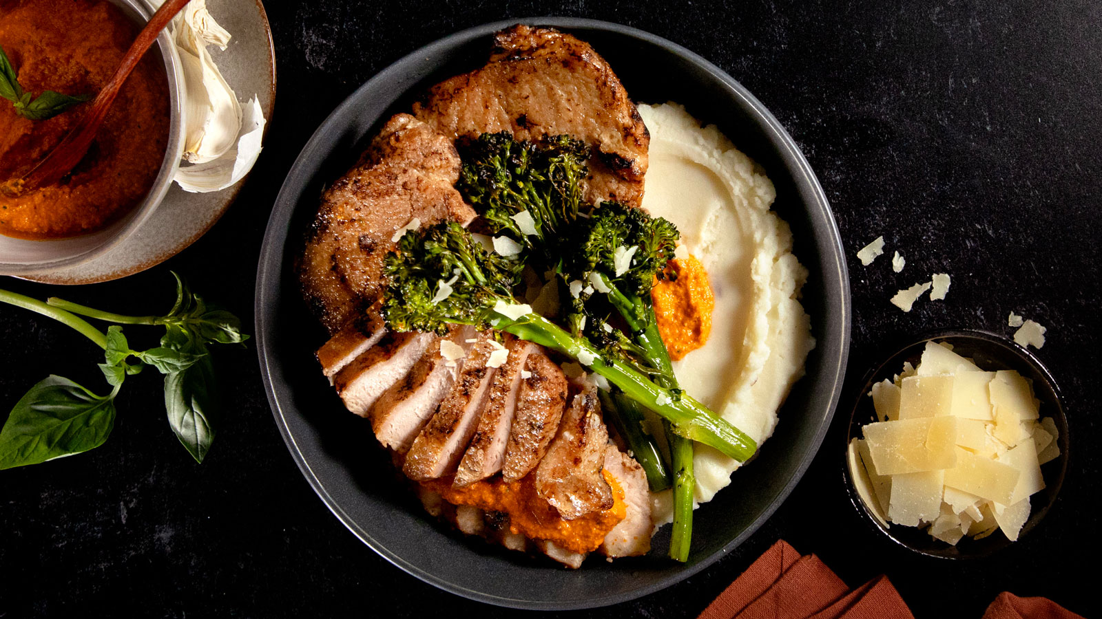 Pork Chops topped with Cashew Romesco Sauce, Truffle Mash, and Broccolini